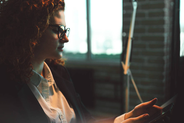 Successful young curly red-haired woman in a business suit and glasses working in an office - Photo, image