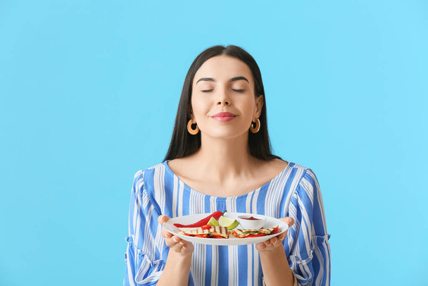 Beautiful young woman with tasty quesadilla on color background - Photo, Image