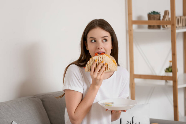 Kaunis nuori nainen syö maukasta quesadillaa kotona - Valokuva, kuva