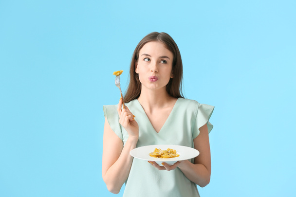 Belle jeune femme mangeant des raviolis savoureux sur fond de couleur - Photo, image