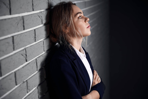 Молодая депрессивная деловая женщина возле кирпичной стены - Фото, изображение