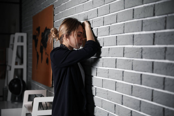 Young depressed businesswoman in dark office - Fotografie, Obrázek