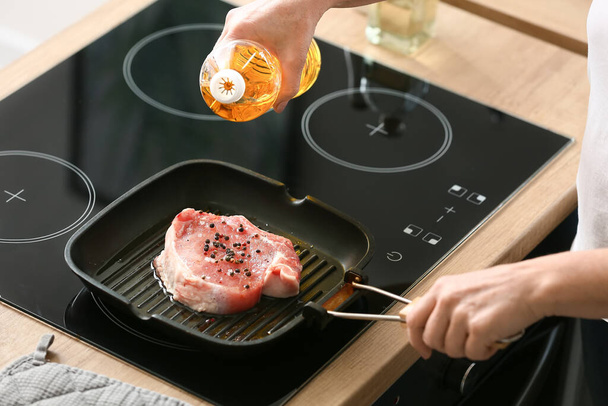 Reife Frau braten frisches Fleisch in der Küche - Foto, Bild