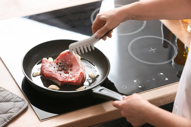 Kypsä nainen paistamista lihaa keittiössä - Valokuva, kuva