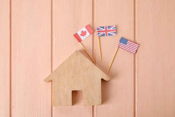 Bandeiras de diferentes países e figura da casa no fundo de madeira - Foto, Imagem