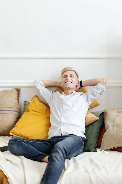 Smiling casual guy relaxing and daydreaming on sofa at home. - Photo, Image