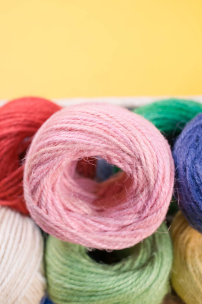 A vertical shot of colorful yarns on a box isolated on yellow background - Foto, imagen