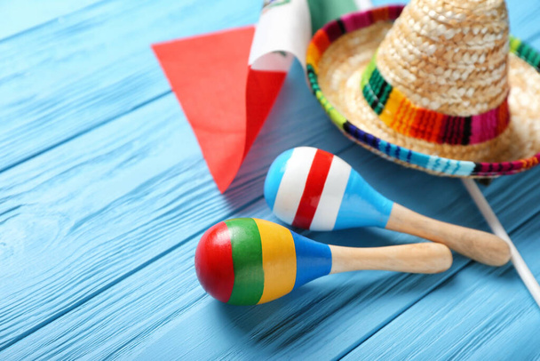 Mexican flag, maracas and sombrero on color wooden background - Photo, Image