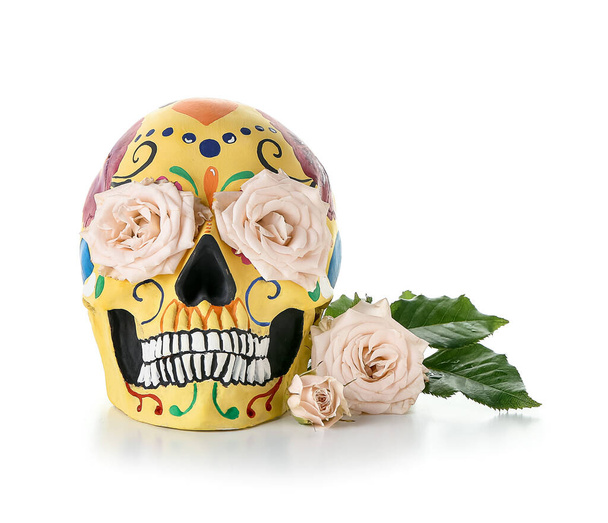 Crâne humain peint pour la fête des morts du Mexique (El Dia de Muertos) et fleurs sur fond blanc - Photo, image
