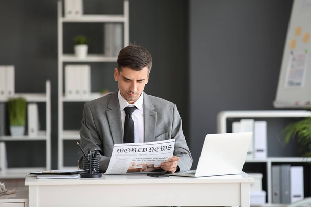 Młody biznesmen czytający gazety w biurze - Zdjęcie, obraz