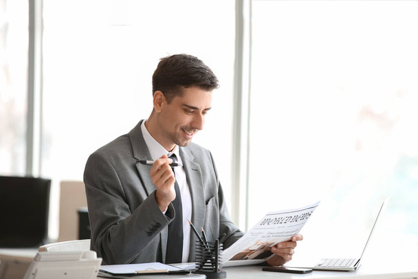 Young businessman reading newspaper in office - Foto, Imagen