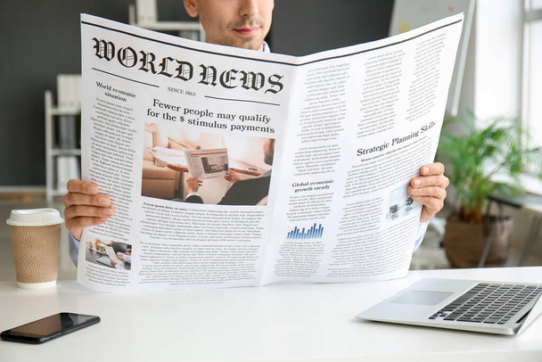 Fiatal üzletember olvas újságot az irodában, közelkép - Fotó, kép