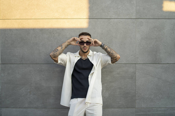 A  Spanish bearded attractive young male leaning on the wall  posing in stylish clothes - Foto, Imagem
