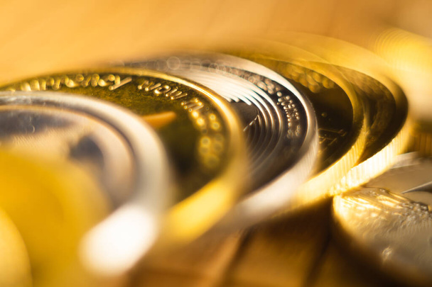 Крупный план золотых и серебряных монет, разбросанных по поверхности, освещенной ярким светом - Фото, изображение