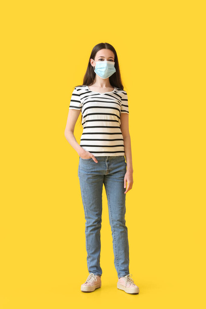 Young woman wearing medical mask on color background - Foto, afbeelding