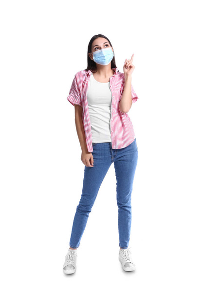Young woman with medical mask showing something on white background - Valokuva, kuva