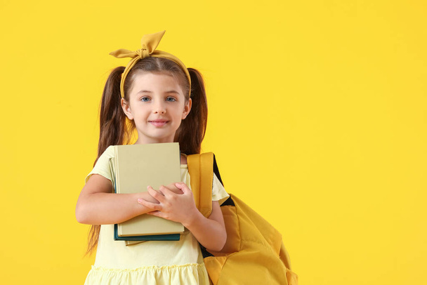 Cute little school girl with books on color background - Photo, Image