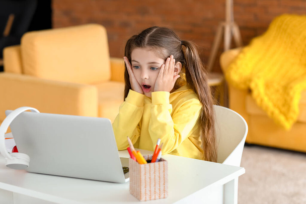 Shocked little girl studying online at home - Foto, imagen