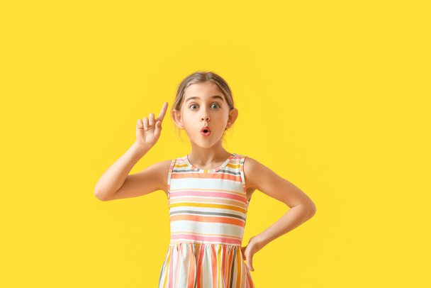 Emotional little girl with raised index finger on color background - Foto, Imagen