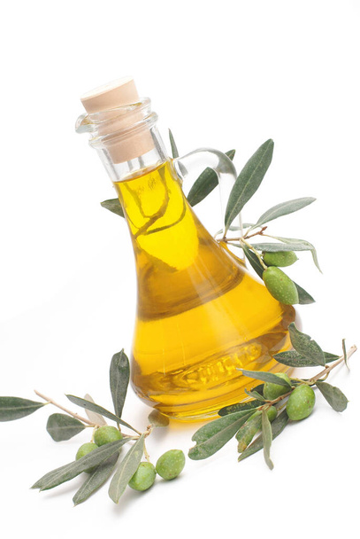 Carafe with olive oil and a fresh twig of olives with leaves, isolated on a white background - Foto, afbeelding
