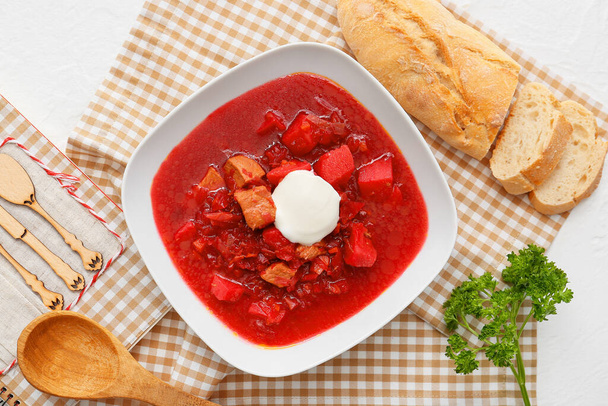 Tigela de borscht saboroso com creme de leite e pão fresco no fundo leve - Foto, Imagem