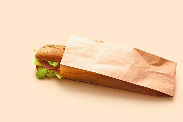 Saco com saboroso sanduíche ciabatta no fundo de cor - Foto, Imagem