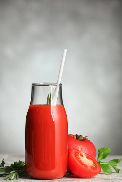 Botella de sabroso jugo de tomate sobre fondo gris - Foto, Imagen
