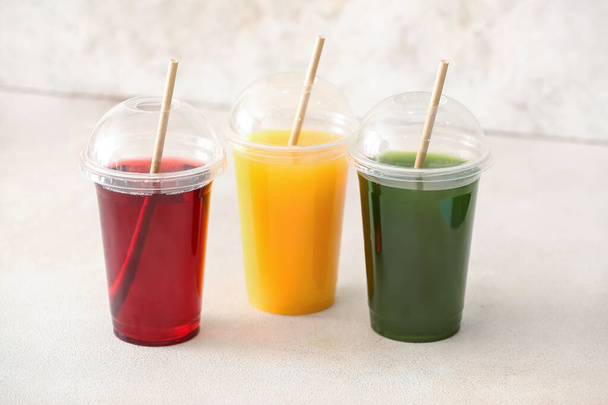 Plastic cups with healthy juice on light background - Foto, afbeelding