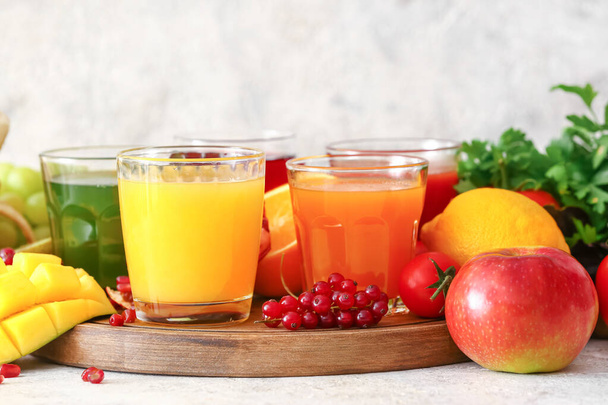 Glasses with healthy juice, fruits and vegetables on light background - Photo, Image