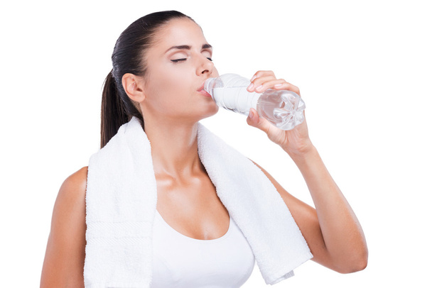 Tired young woman holding bottle with waterd on white - Фото, изображение