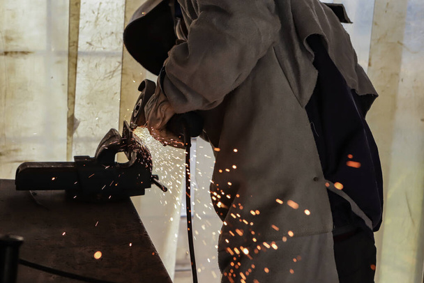 Kimliğini tespit edemeyen bir işçinin yaptığı çelik plakayı öğütme eyleminden kıvılcımlar. - Fotoğraf, Görsel