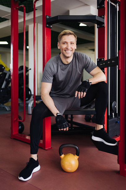 Porträt eines muskulösen Mannes im Fitnessstudio, der in die Kamera blickt. - Foto, Bild