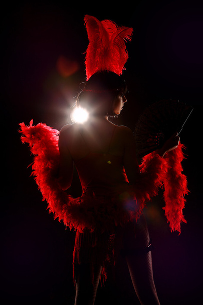 Burlesque dancer with red plumage and short dress, black background - Фото, изображение
