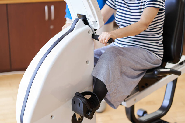 Elderly people exercising on an exercise bike and a caregiver watching over - Photo, Image
