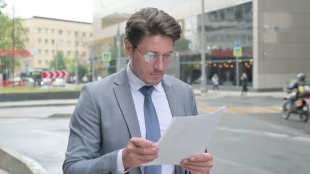 Middle Aged Businessman Reading Documents while Walking on Street - Video, Çekim