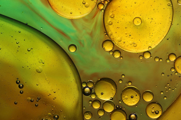 oil bubbles with water on glass and golden background - Photo, Image