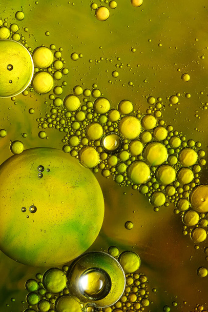 φυσαλίδες πετρελαίου με νερό σε γυάλινο και χρυσό φόντο - Φωτογραφία, εικόνα