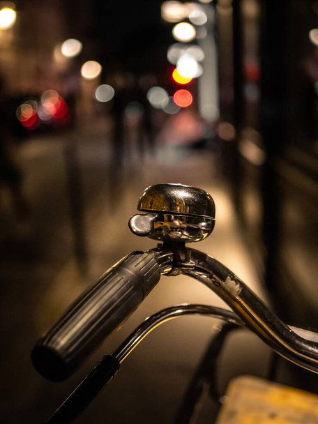 A vertical shot of a bicycle handle and bell, outdoors during nighttime - Foto, Imagen