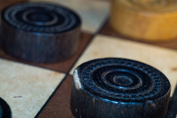 A closeup shot of a checkers board and wooden game pieces on it - Фото, изображение