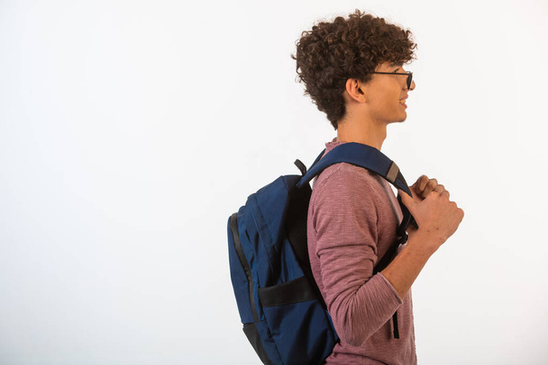 Curly hair boy in optique glasses holding his backpack and going ahead. High quality photo - Фото, зображення