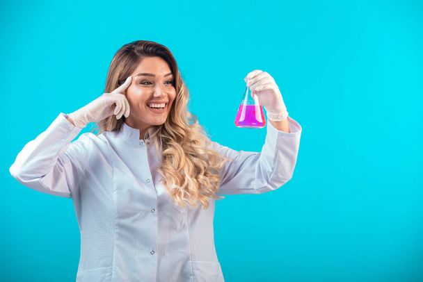 Nurse in white uniform holding a chemical flask with pink liquid. High quality photo - Foto, Imagem