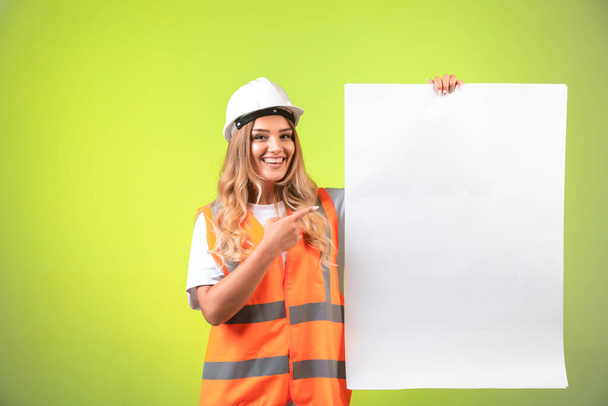 Γυναίκα μηχανικός σε λευκό κράνος και εργαλεία παρουσιάζει το σχέδιο κατασκευής. Υψηλής ποιότητας φωτογραφία - Φωτογραφία, εικόνα