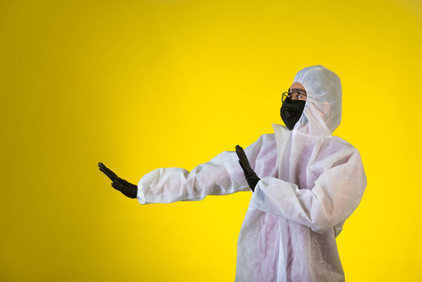 Özel önleyici üniformalı ve maskeli dezenfektan sol taraftan gelen tehlikeyi durdurur. Yüksek kalite fotoğraf - Fotoğraf, Görsel
