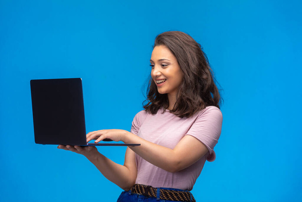  Naispuolinen työntekijä mustalla kannettavalla tietokoneella, jolla on videopuhelu ja hauskaa. Laadukas kuva - Valokuva, kuva