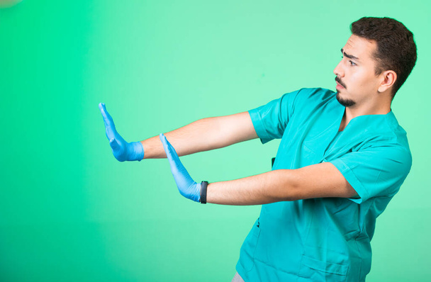 Doutor de uniforme verde e máscaras de mão afastando-se do perigo. Foto de alta qualidade - Foto, Imagem
