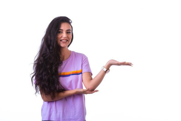 Молода дівчина представляє щось зі знаком руки. Високоякісна фотографія
 - Фото, зображення