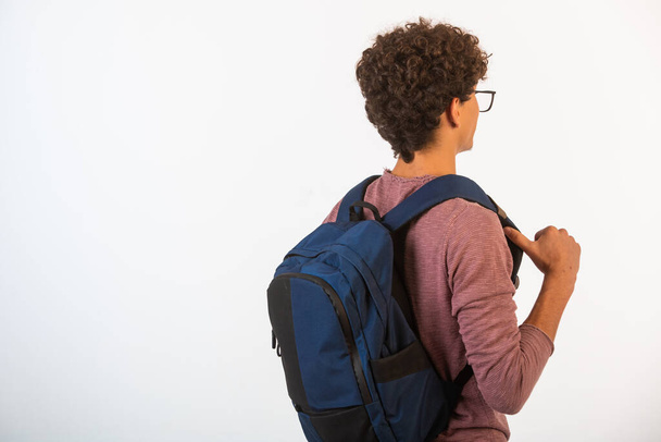 Curly hair boy in optique glasses holding his backpack, view from behind. High quality photo - Photo, Image