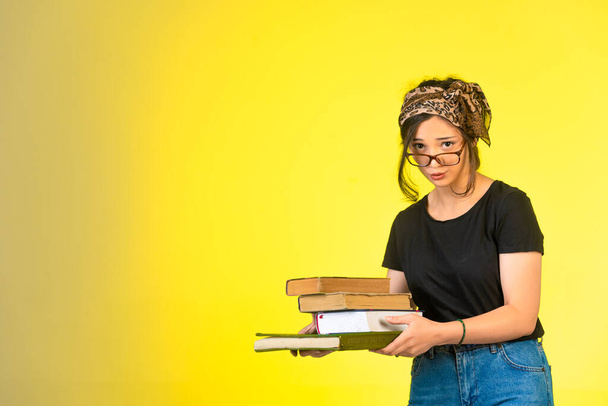 Young schoolgirl in eyeglasses holding her books and over her glasses. High quality photo - Photo, Image