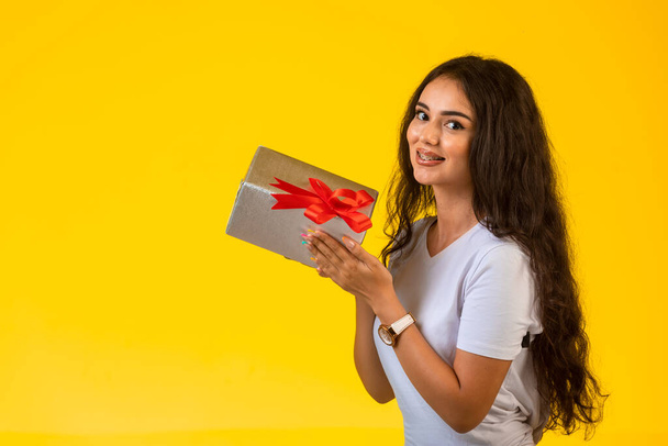 Young girl posing with a gift box in the hand and feeling positive. High quality photo - Photo, Image