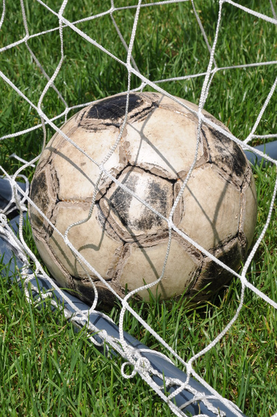 Vieja pelota de fútbol en la red de gol
 - Foto, imagen